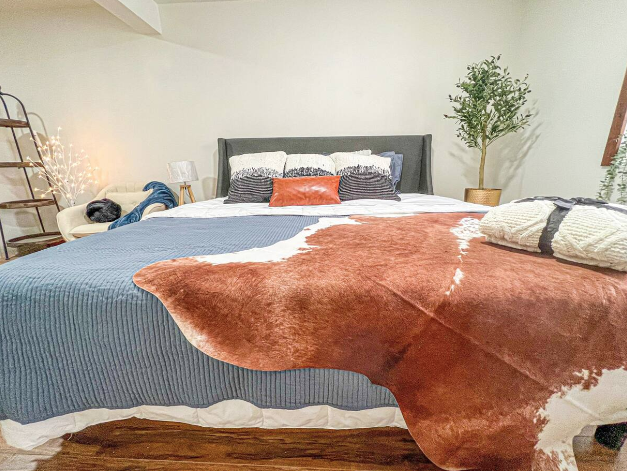 king bed with blue bedspread and animal hide draped at the foot
